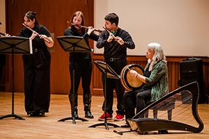 Three students with teacher playing music.