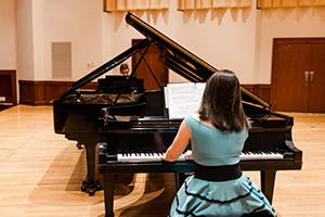 Students playing piano on stage.