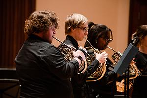 Three students playing brass instruments.